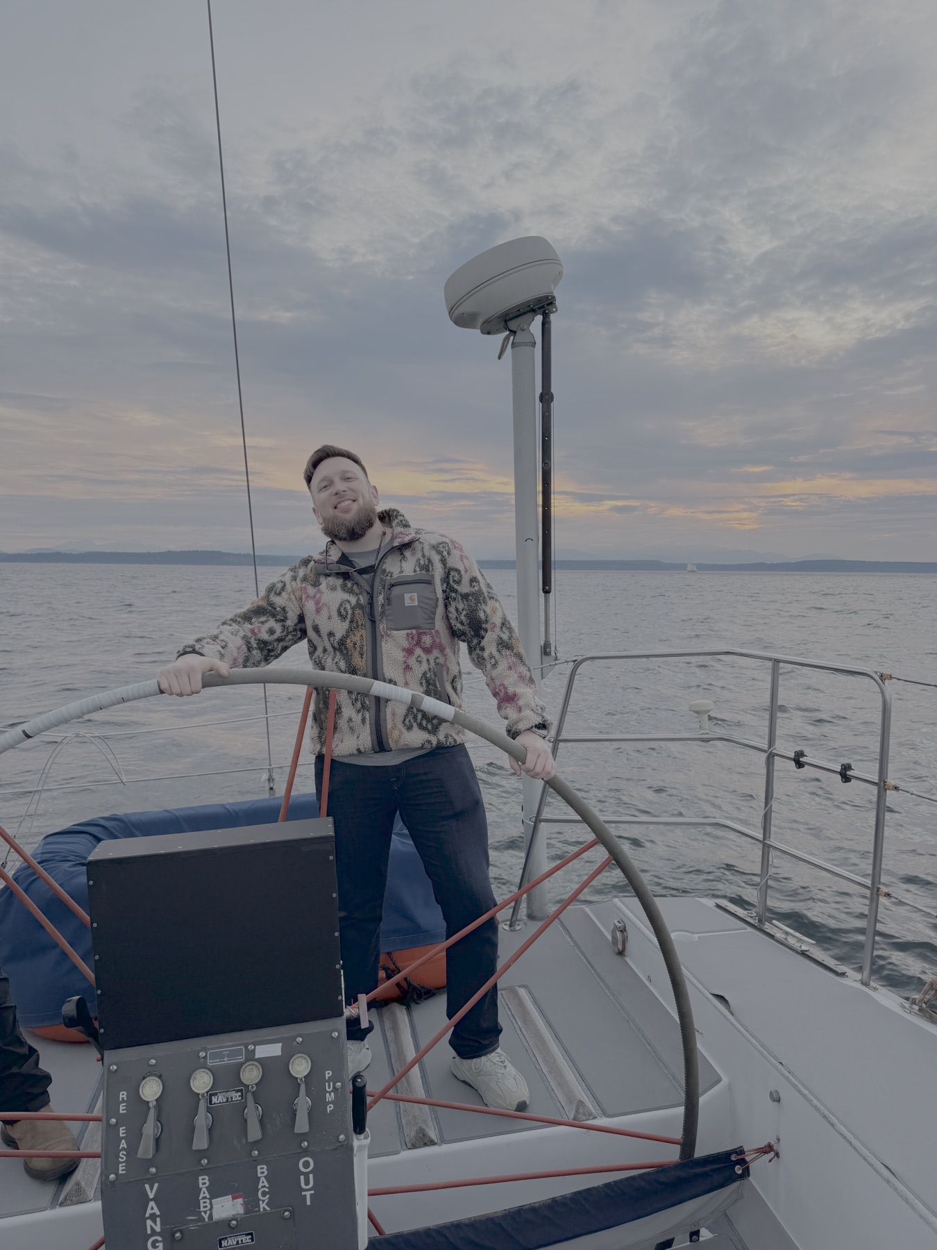 Nathan Haynes at the wheel of a sailboat at sunset