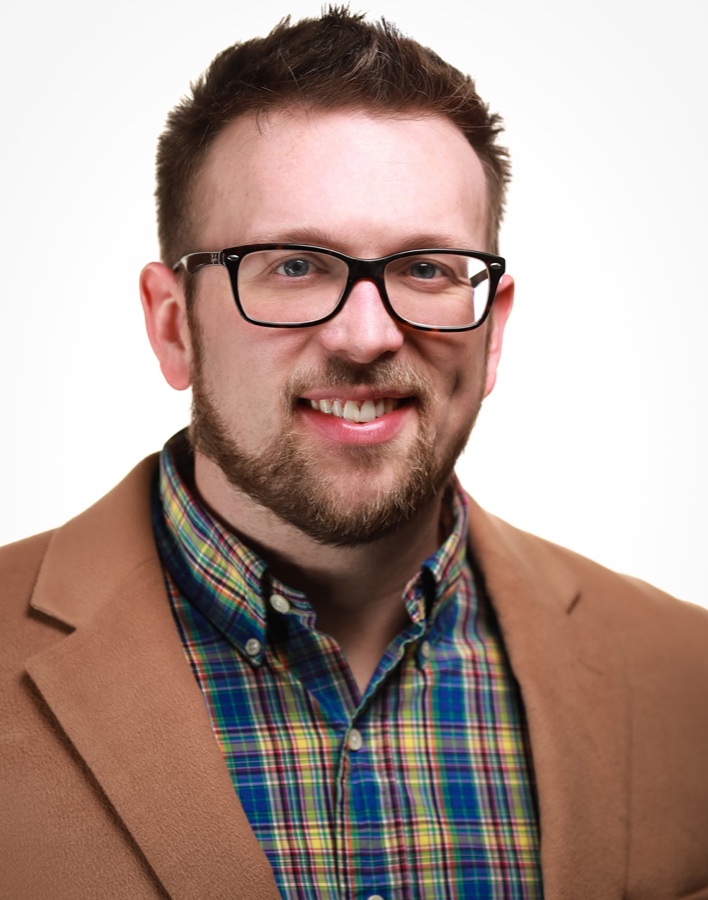 Nathan Haynes wearing glasses and a tan blazer